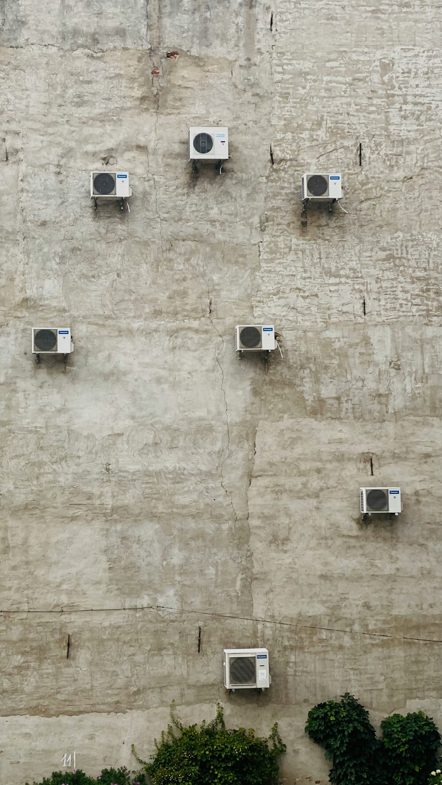 a wall with many air conditioners on it